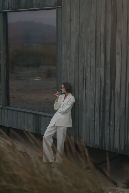 A Woman in a White Suit Smoking a Cigarette