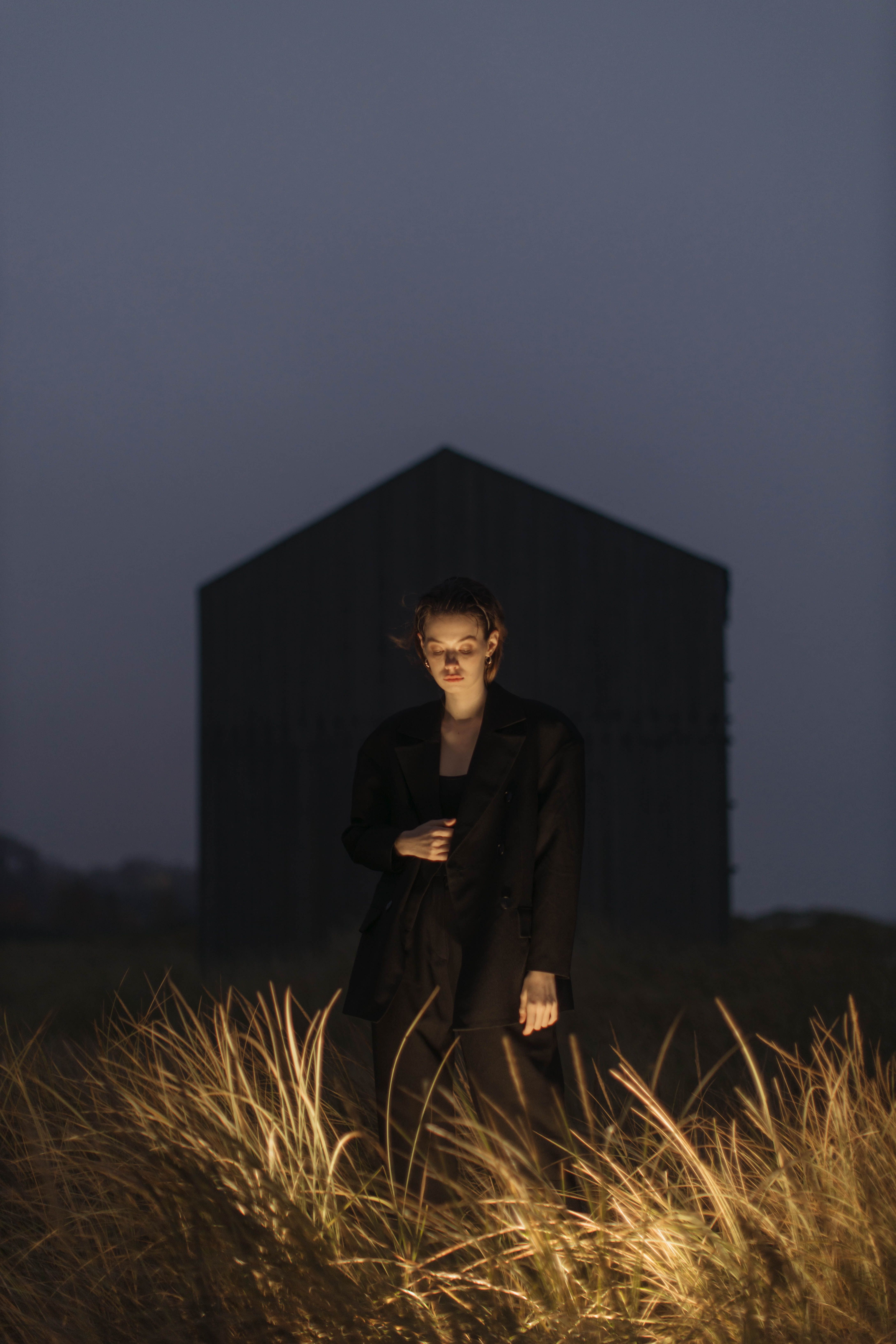 A Woman in Black Coat Standing on the Lit Green Grass · Free Stock Photo