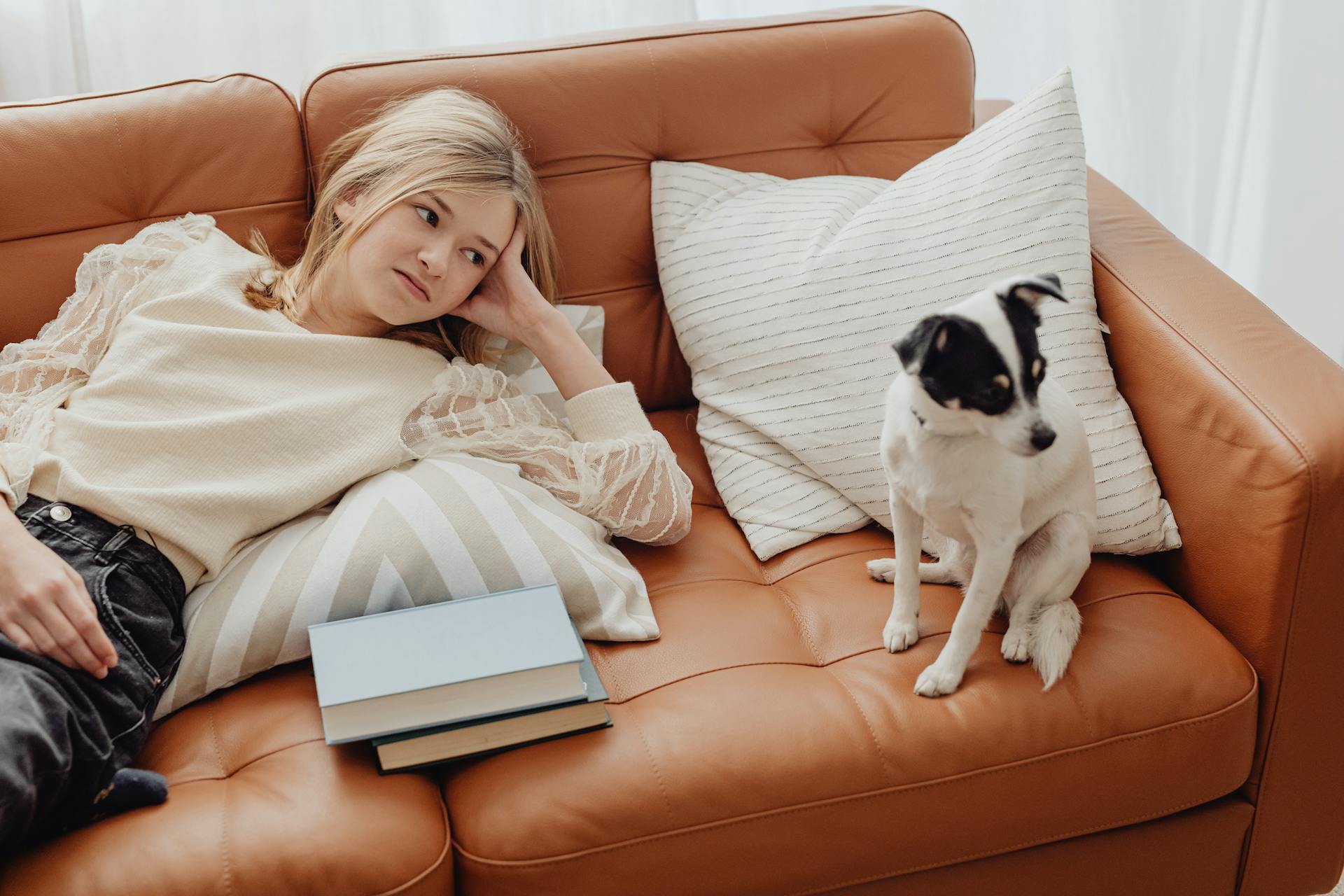 A Woman Lying Down on the LEather Couch with a Puppy