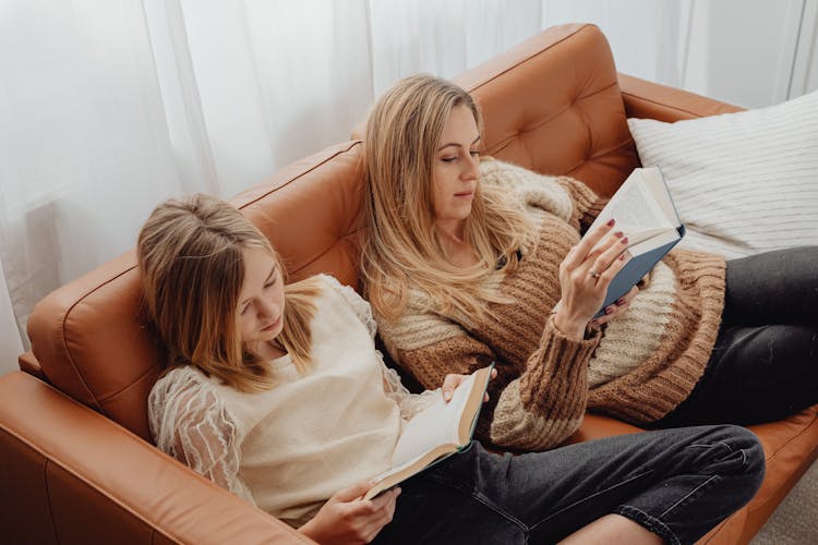 Mother And Daughter Reading Books On A Sofa 