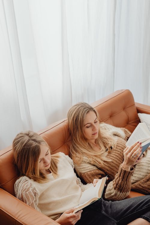 Free A mother and daughter enjoy a cozy reading session together on a comfortable sofa, creating a warm family moment. Stock Photo