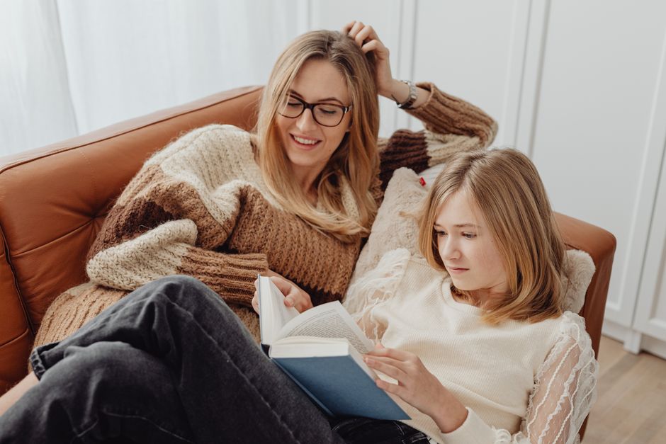 Mother and daughter enjoying a quiet reading time on a comfy sofa indoors.