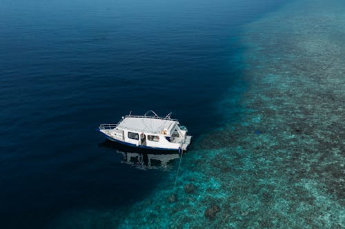 Scenery of modern yacht moored on clear turquoise seawater near coral reefs on clear weather