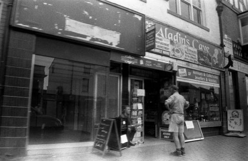 Free A black and white photo of a vintage urban scene featuring a storefront and pedestrians. Stock Photo