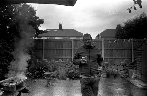 Happy Man on a Barbecue in the Backyard Holding a Cup 