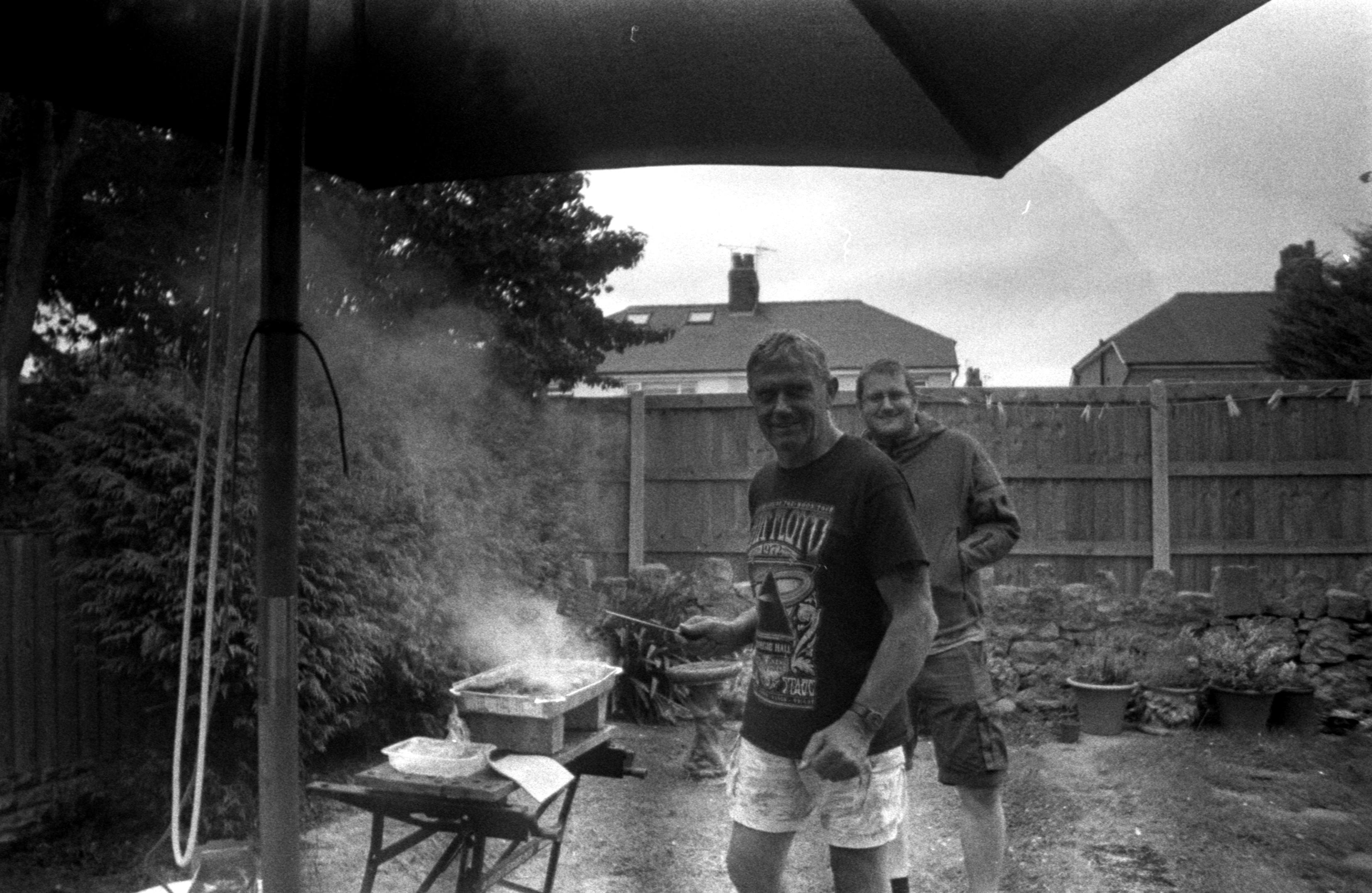 Enjoy a nostalgic backyard barbecue captured in classic black and white film, showcasing a joyful summer gathering.