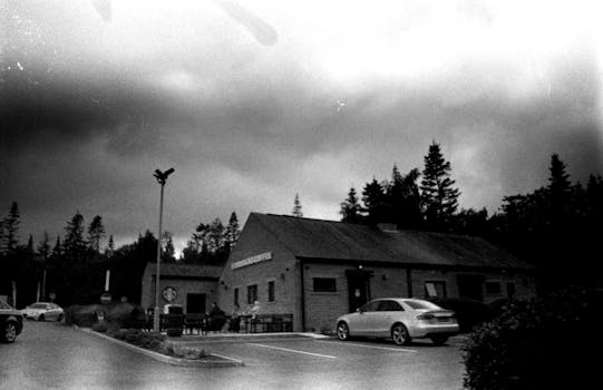 Moody black and white coffee shop exterior with cars in the parking lot.