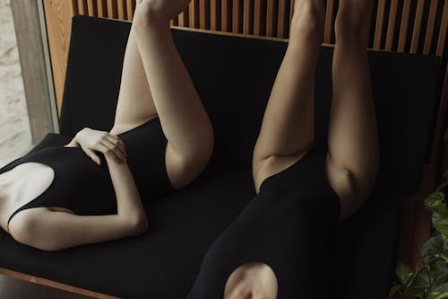 Free Women in Bodysuits Lying Down on a Chair Stock Photo
