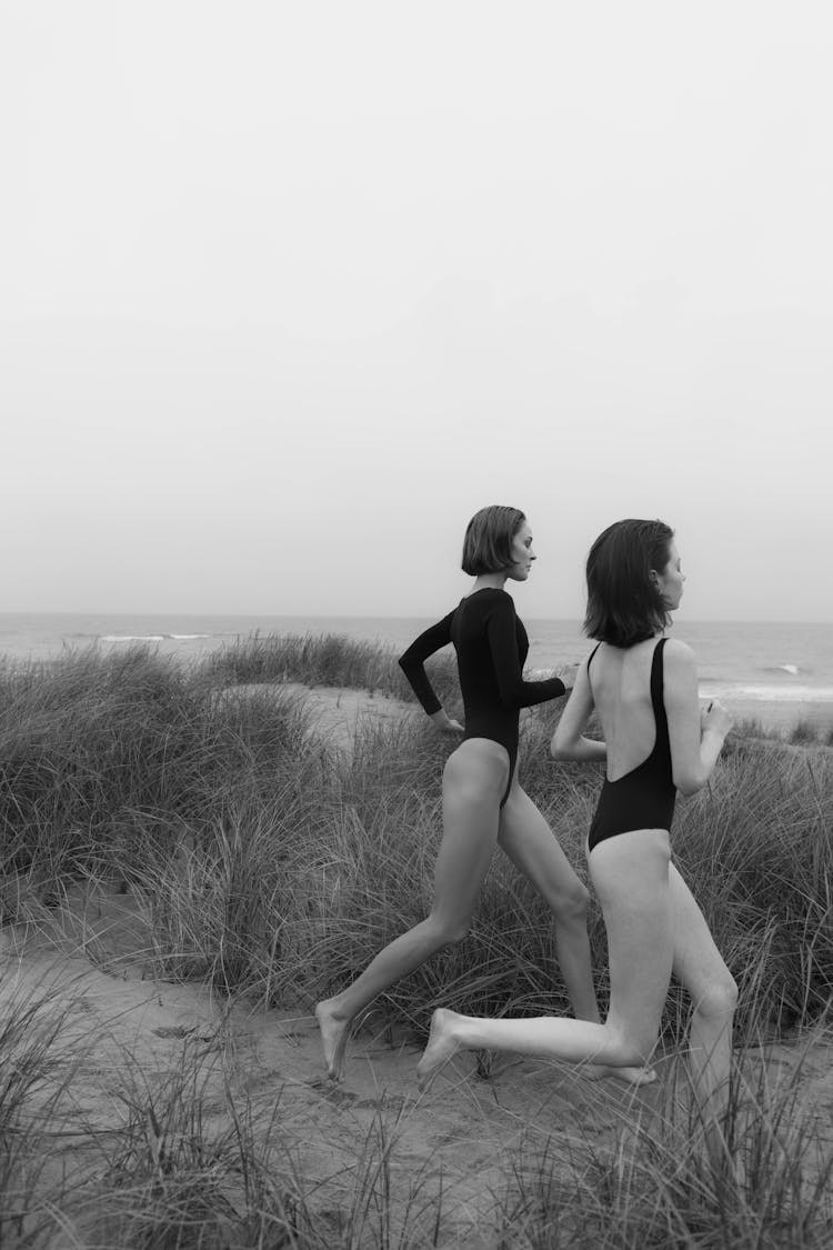 A Grayscale Of Women In Bikinis Running