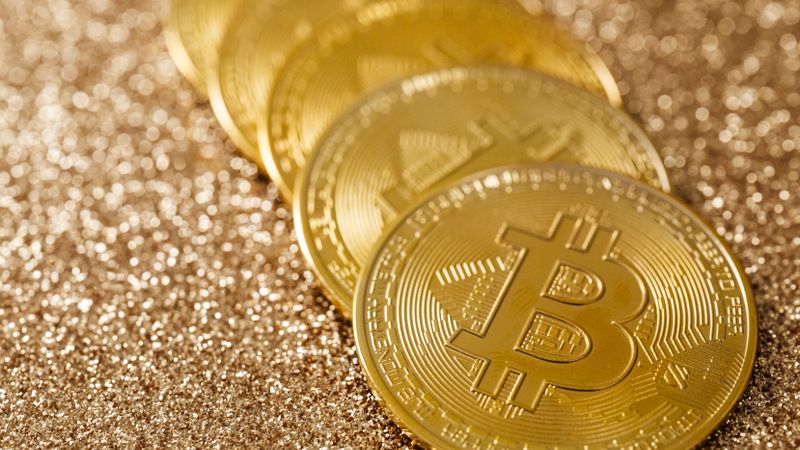 Close-up of golden Bitcoin coins on a shimmering glitter background, symbolizing digital currency's allure.