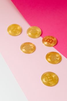 金色比特币在粉色和白色表面上展示，象征着加密货币投资