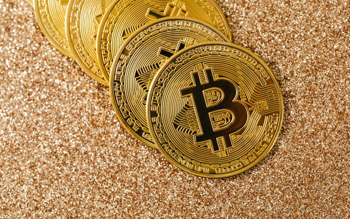 Golden Bitcoin coins arranged on a sparkling glitter surface, symbolizing cryptocurrency and wealth.