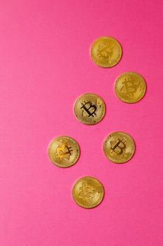 Gold Bitcoin coins arranged on a striking pink background, showcasing cryptocurrency appeal.