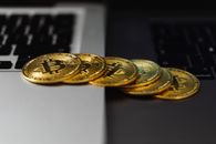笔记本电脑键盘上放着一堆比特币，象征着数字货币和金融
