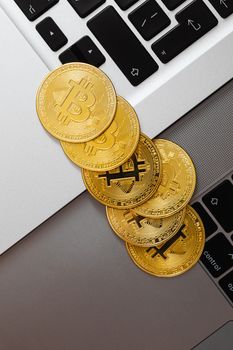 黄金比特币俯视图放置在笔记本电脑键盘上，象征着数字货币和金融技术