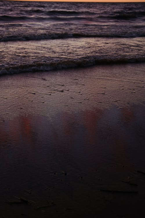Sandy seashore with waterdrops and endless waving ocean in nature on evening time in tropical resort at sunset in summer