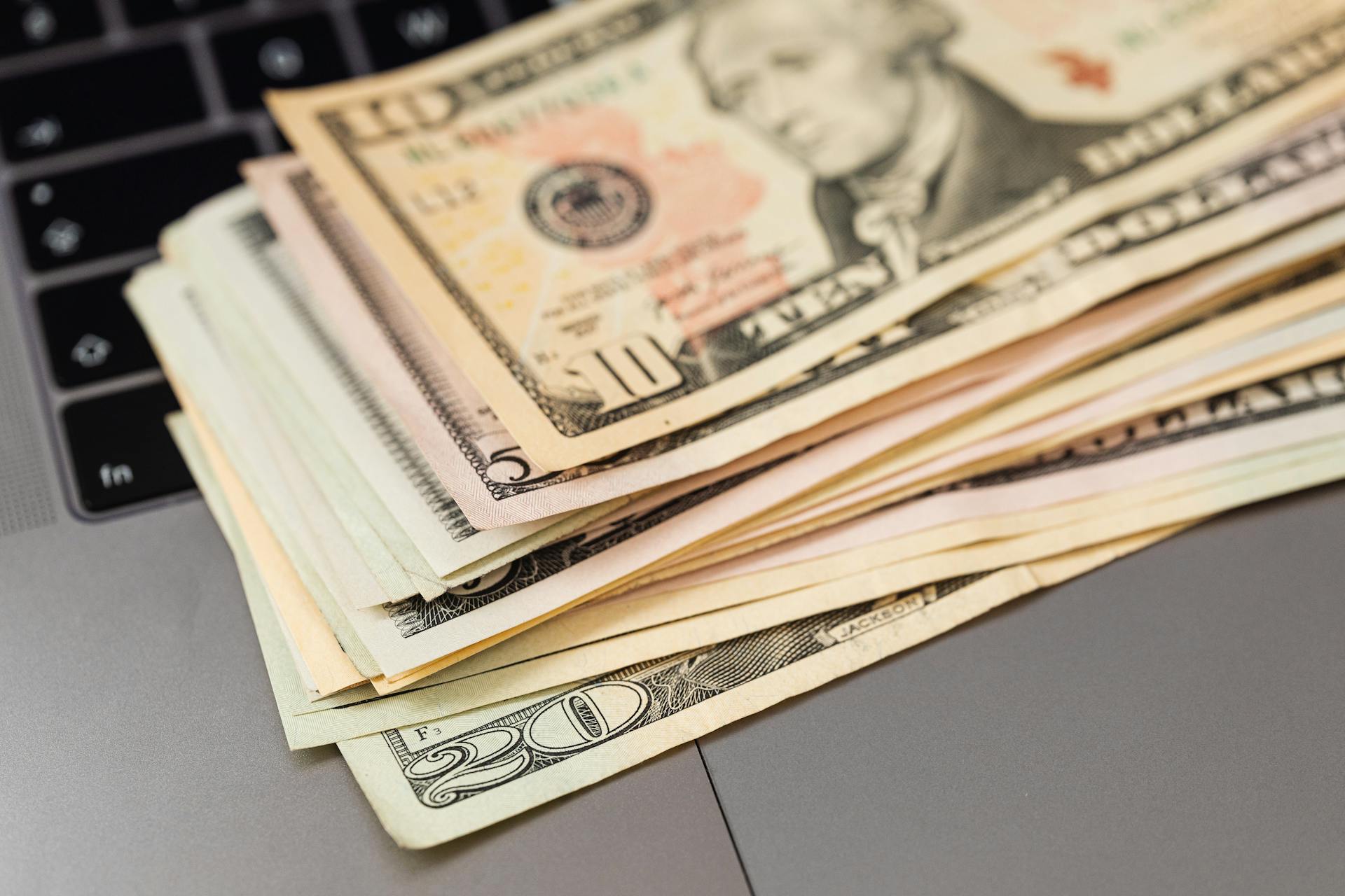 Stack of US dollar bills on a keyboard, symbolizing digital finance and wealth.