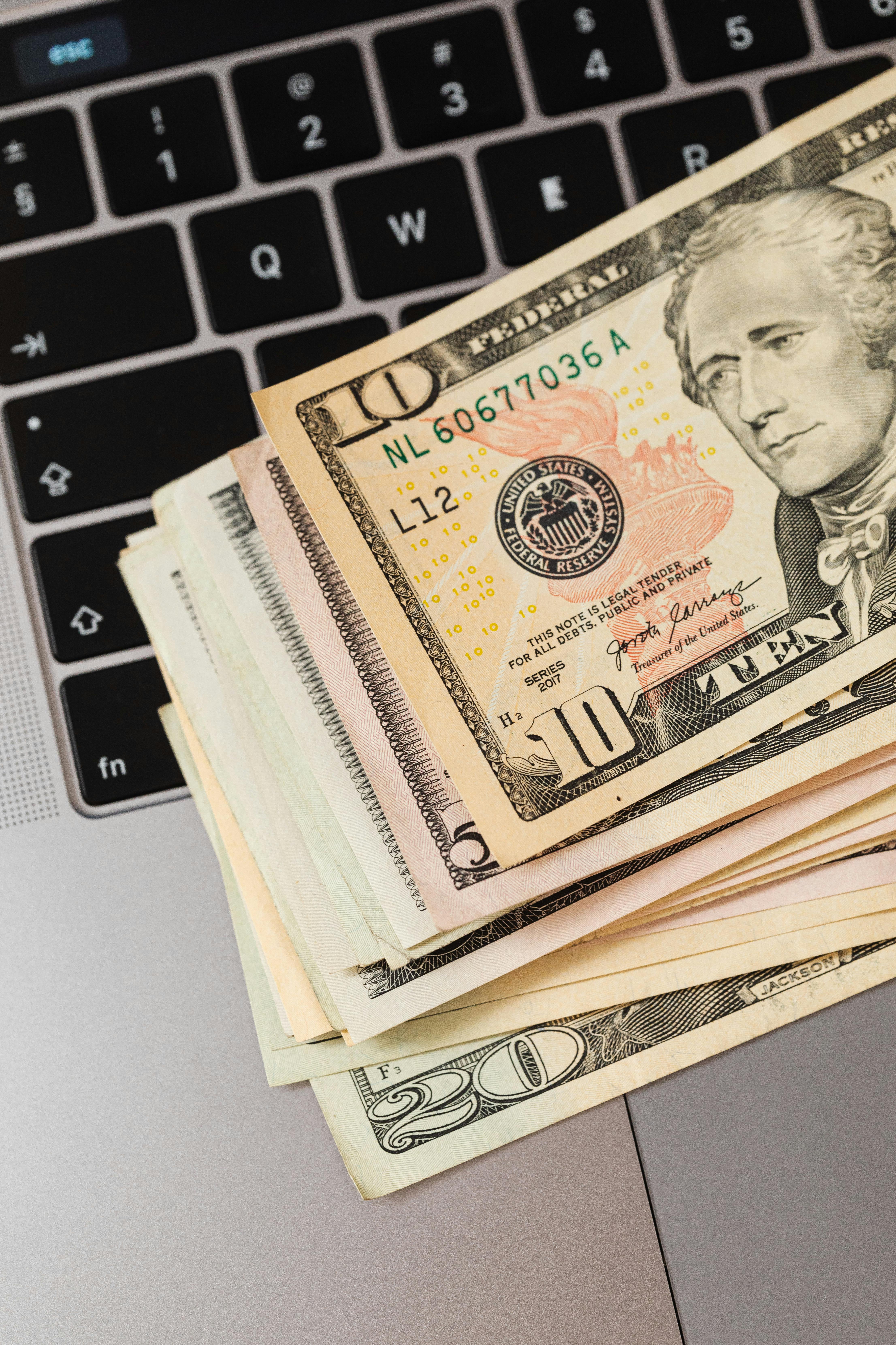 Close-up of US dollar bills stacked on a laptop keyboard, representing online finance.