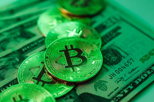 Close-up of Cash and Bitcoin Coins in Green Lighting