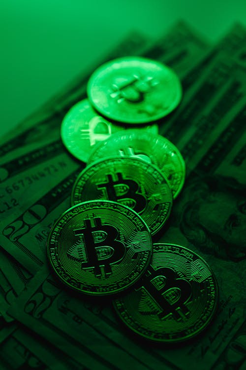 Bitcoins on Dollar Bills in Green Light