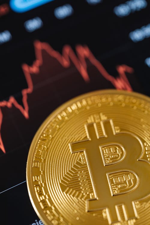 Close-up of a Gold Bitcoin Coin with Graphs in the Background 