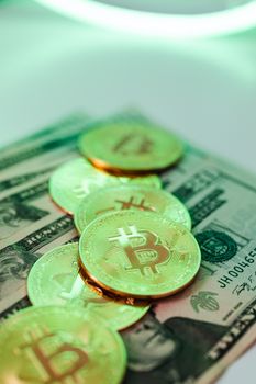 Golden Bitcoin coins placed over American dollar banknotes, highlighting crypto and cash economy.