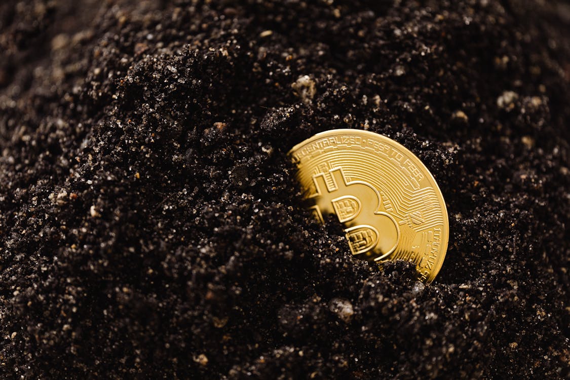 Blockchain In Real Estate - Bitcoin Buried In The Ground Stock Photo