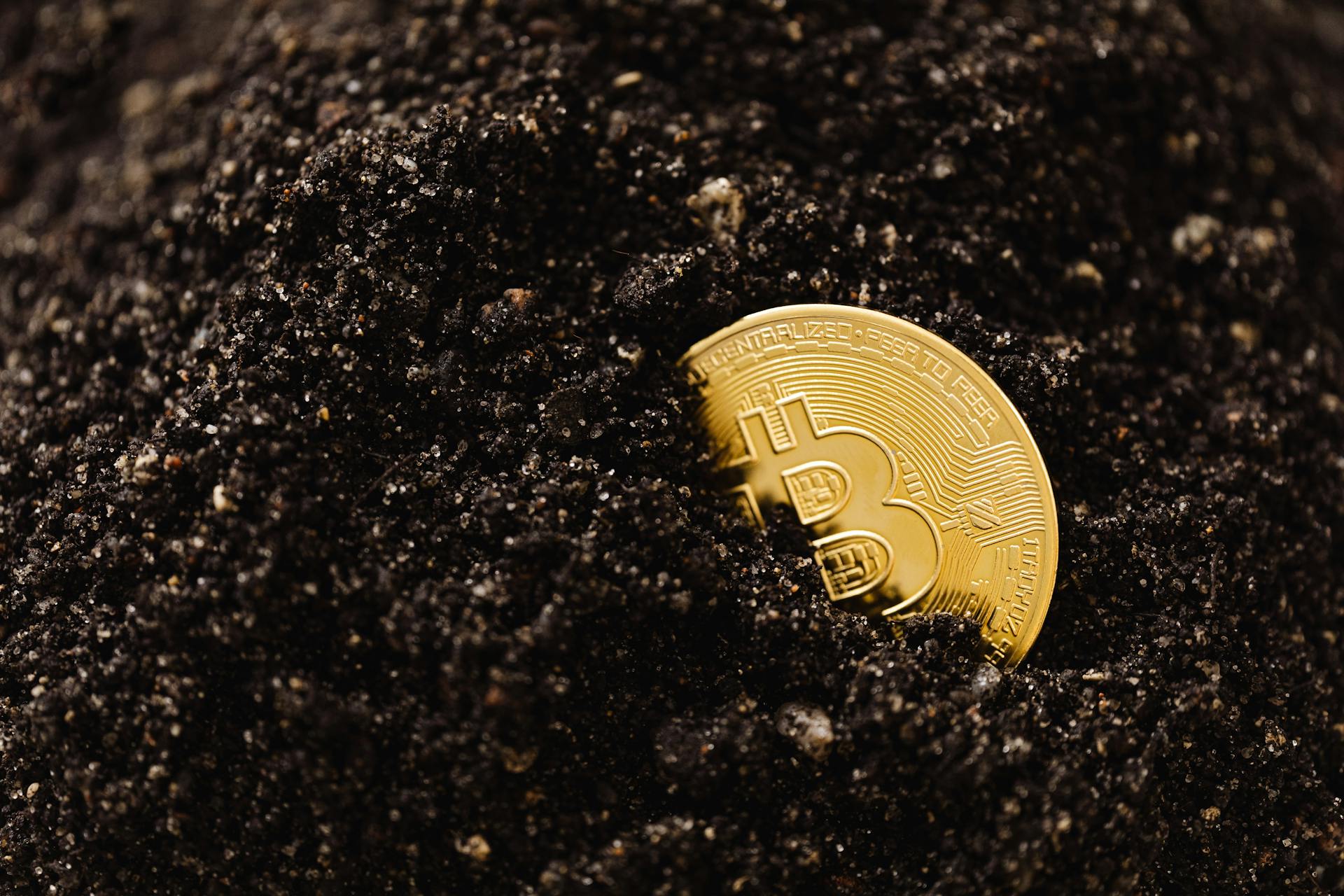 Close-Up Shot of a Bitcoin Buried in the Ground