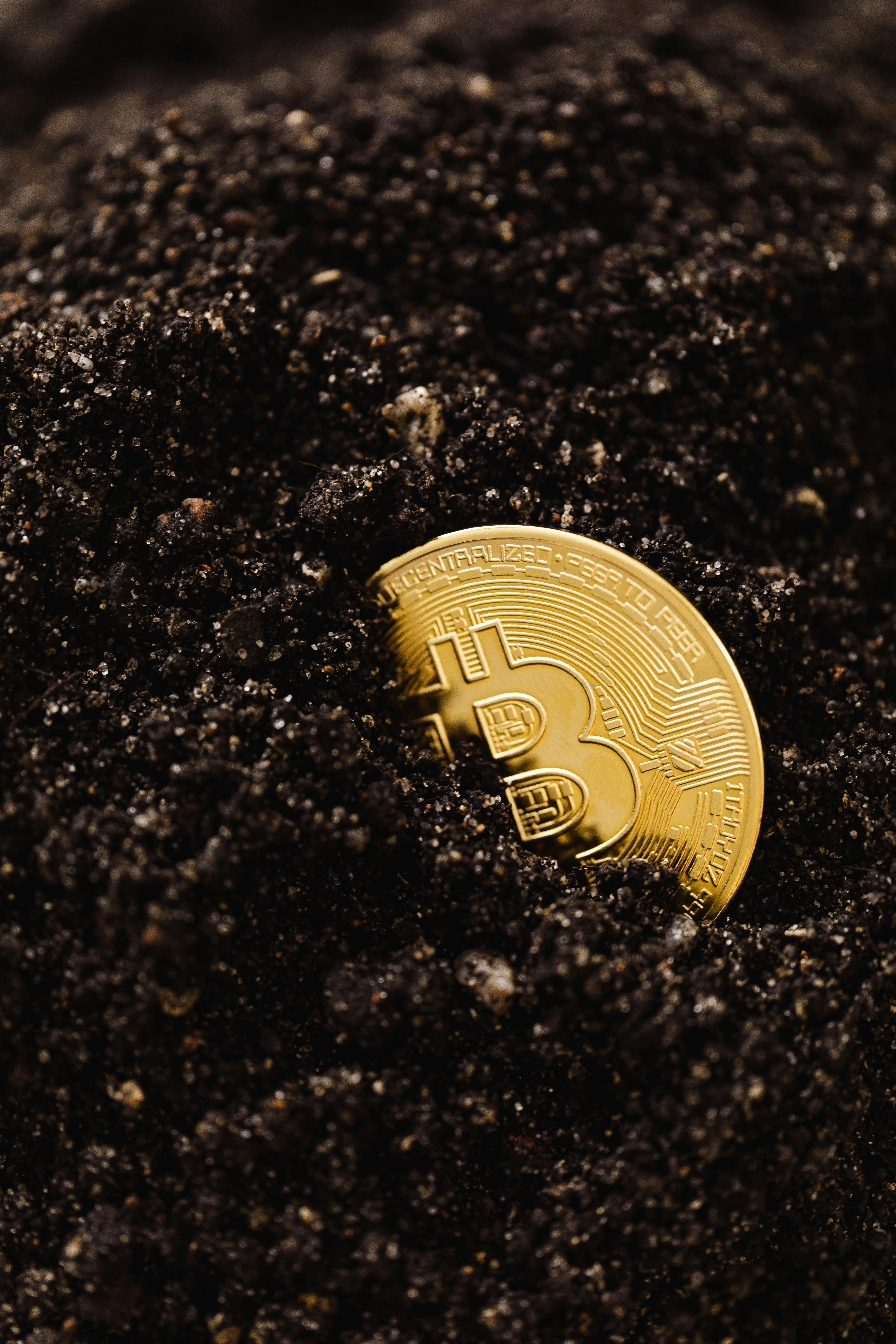 close up shot of a bitcoin buried in the ground