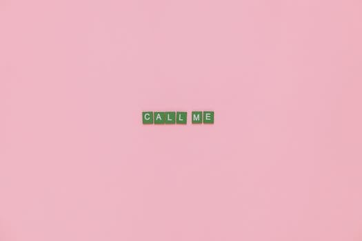 Scrabble letters forming 'CALL ME' on a pink background, offering creative copyspace.