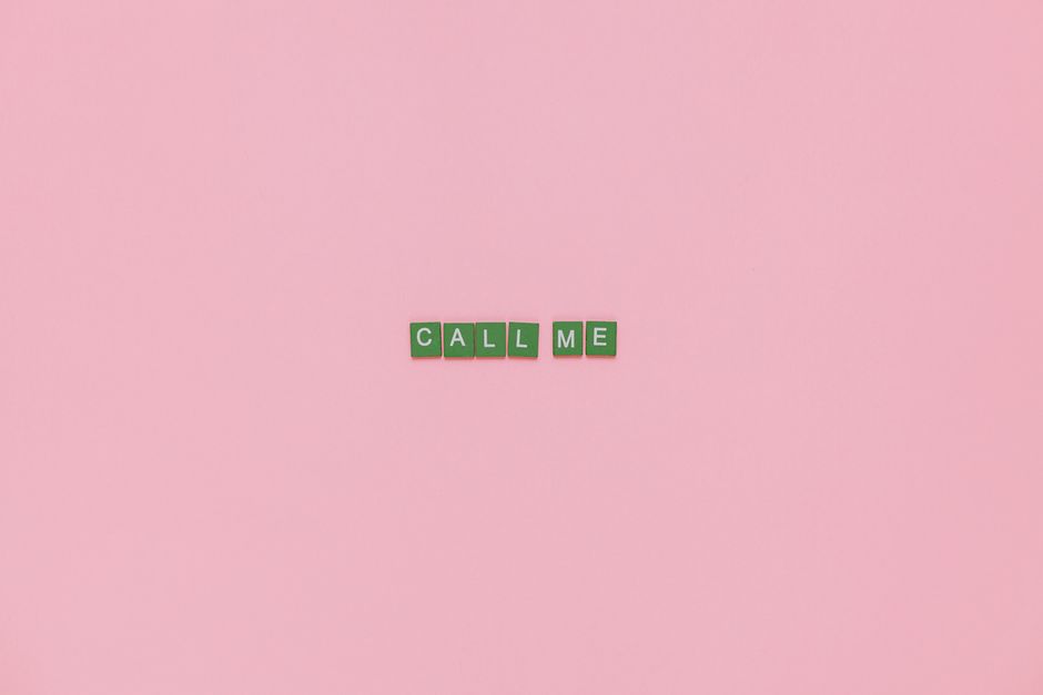 Scrabble letters forming 'CALL ME' on a pink background, offering creative copyspace.