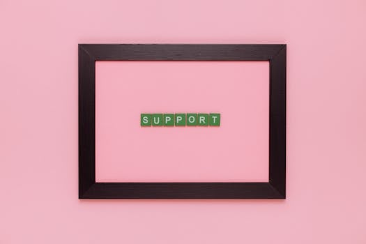 Green 'support' letters in a black frame on a pink backdrop, conveying positivity.