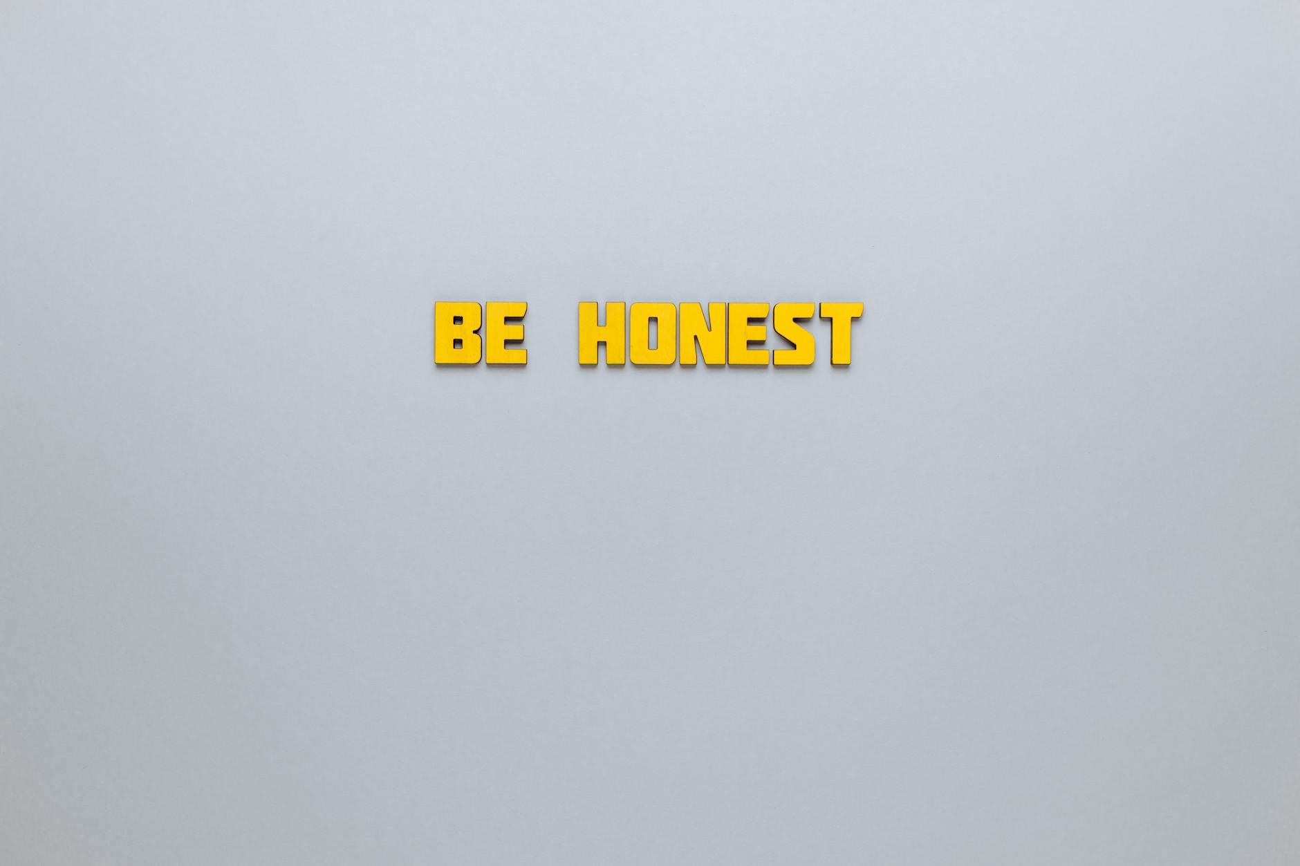 Simple yellow text 'Be Honest' on a neutral background, emphasizing clarity and inspiration.