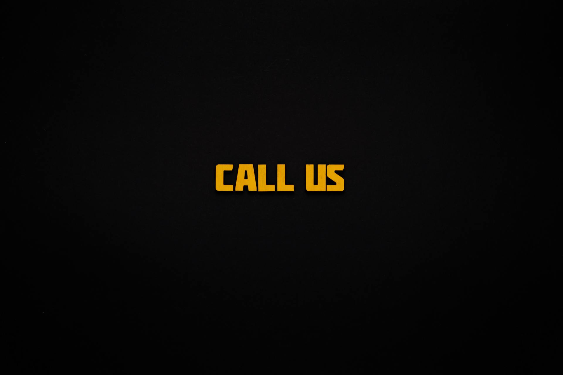 Minimalist design featuring the text 'Call Us' in yellow on a black background for communication-themed visuals.