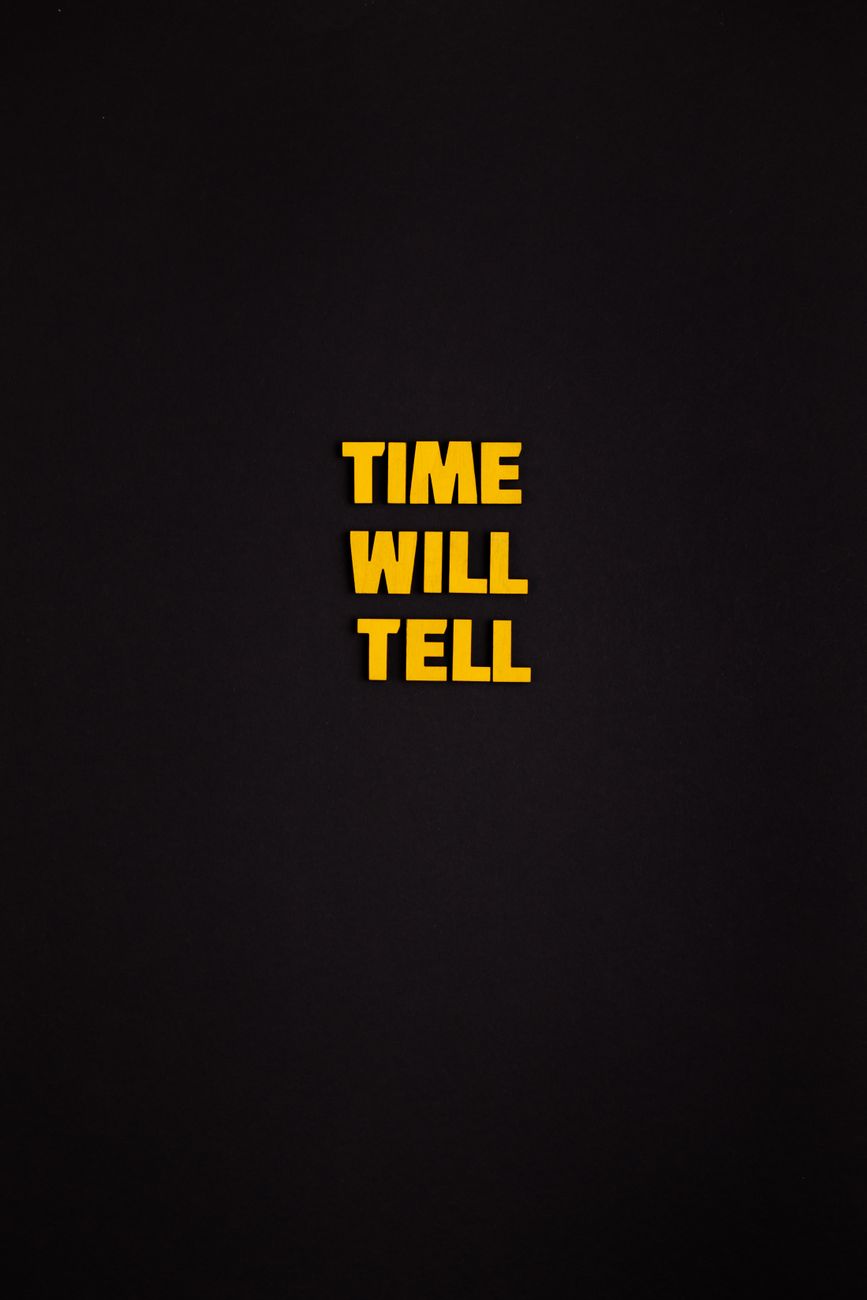 Yellow text spells 'Time Will Tell' against a simple black background, offering modern minimalism.