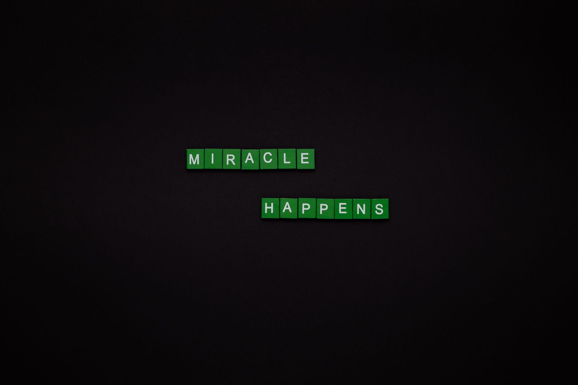Motivational image featuring the words 'Miracle Happens' using green tiles on a black backdrop.