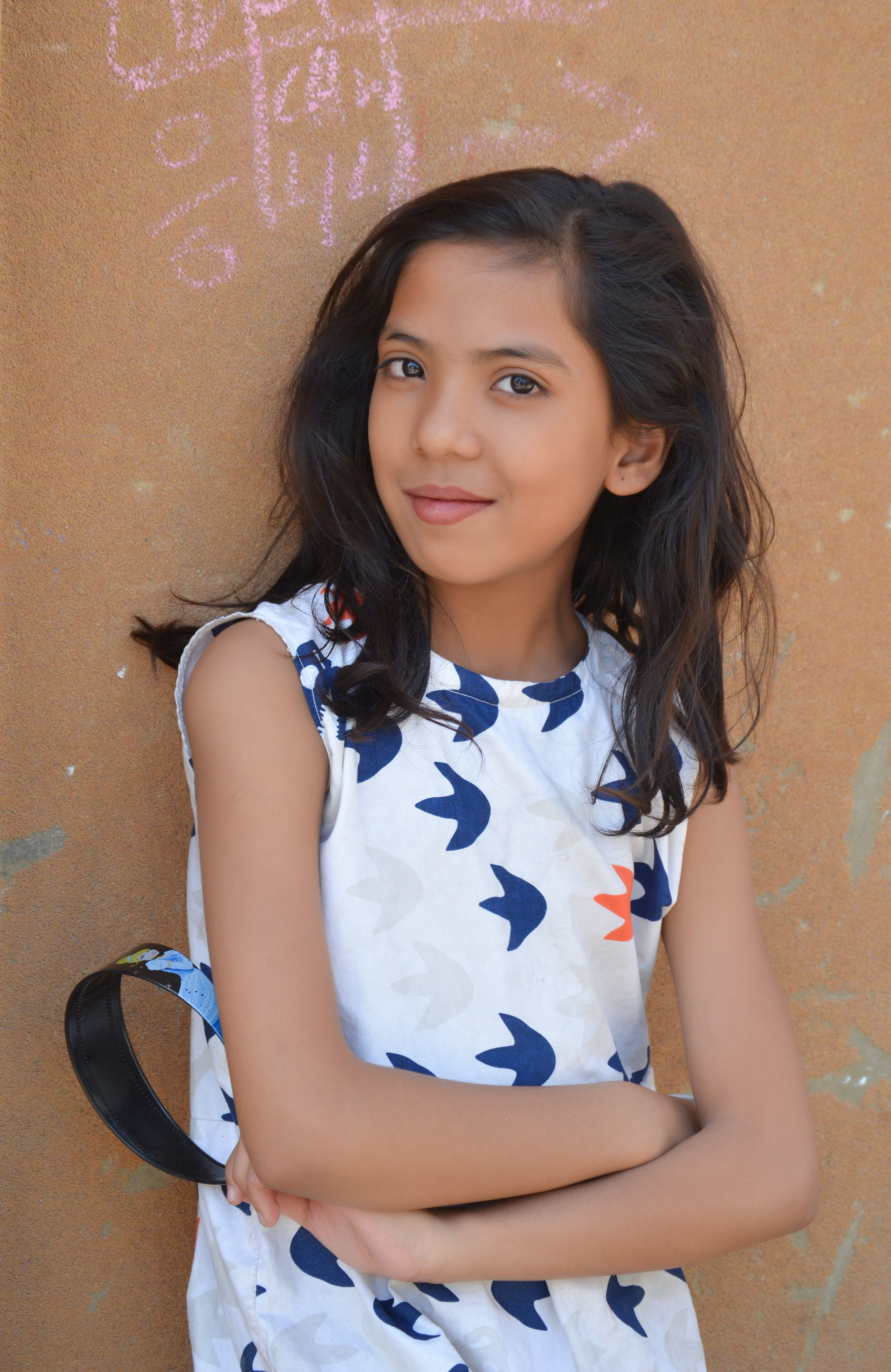 Charming young girl posing outside in Karachi wearing a sleeveless dress.