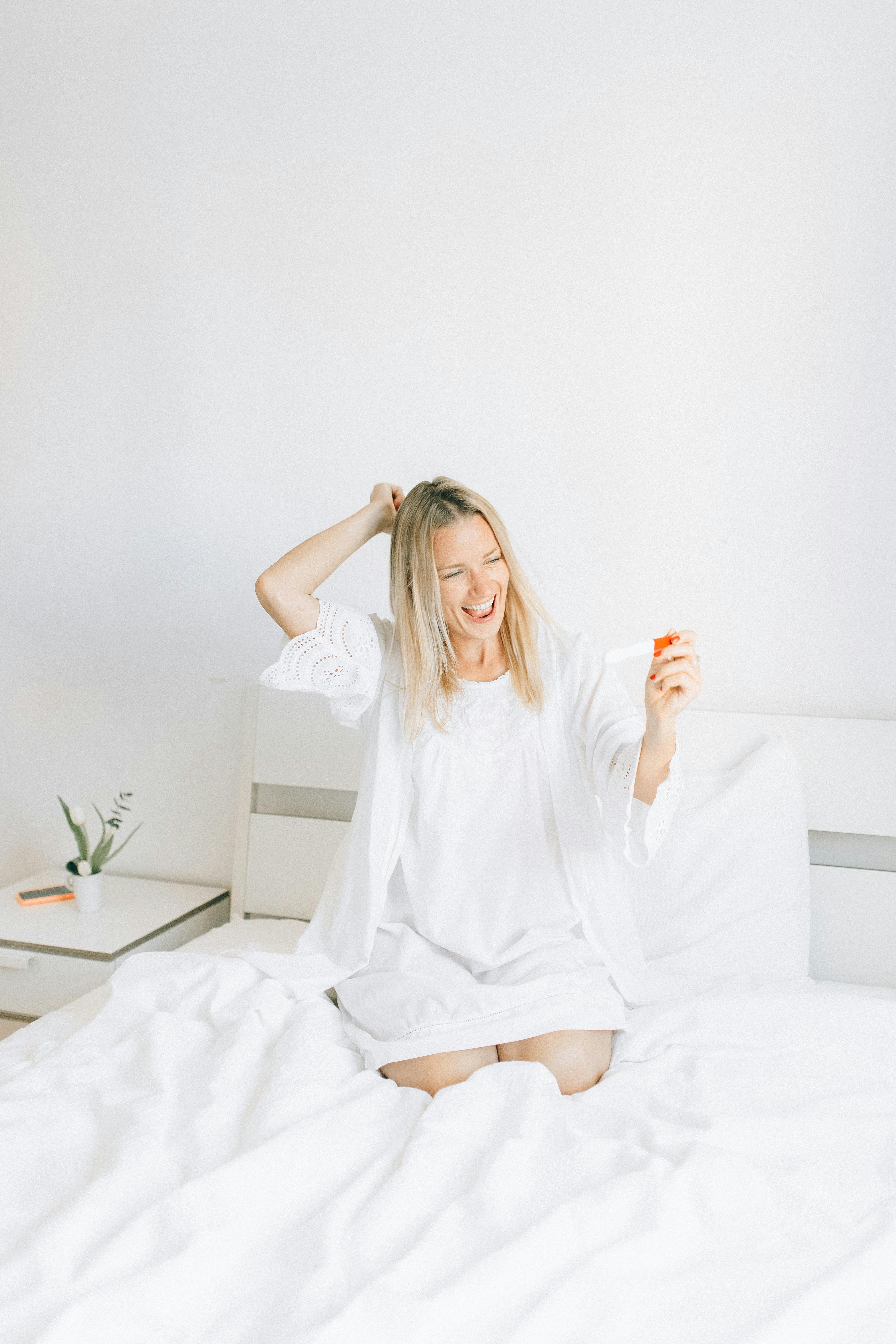 woman holding a pregnancy test on the bed