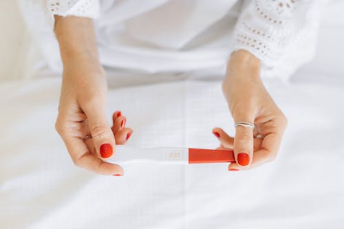 Person Wearing Silver Ring Holding White and Red Paper