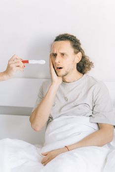 一名男子在卧室里看到验孕棒时，露出了惊讶的表情