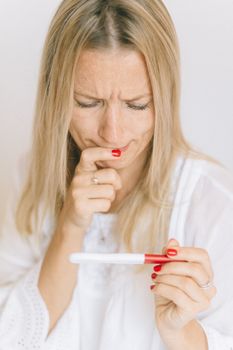一名女子拿着验孕棒，表情焦虑，流露出期待与不安