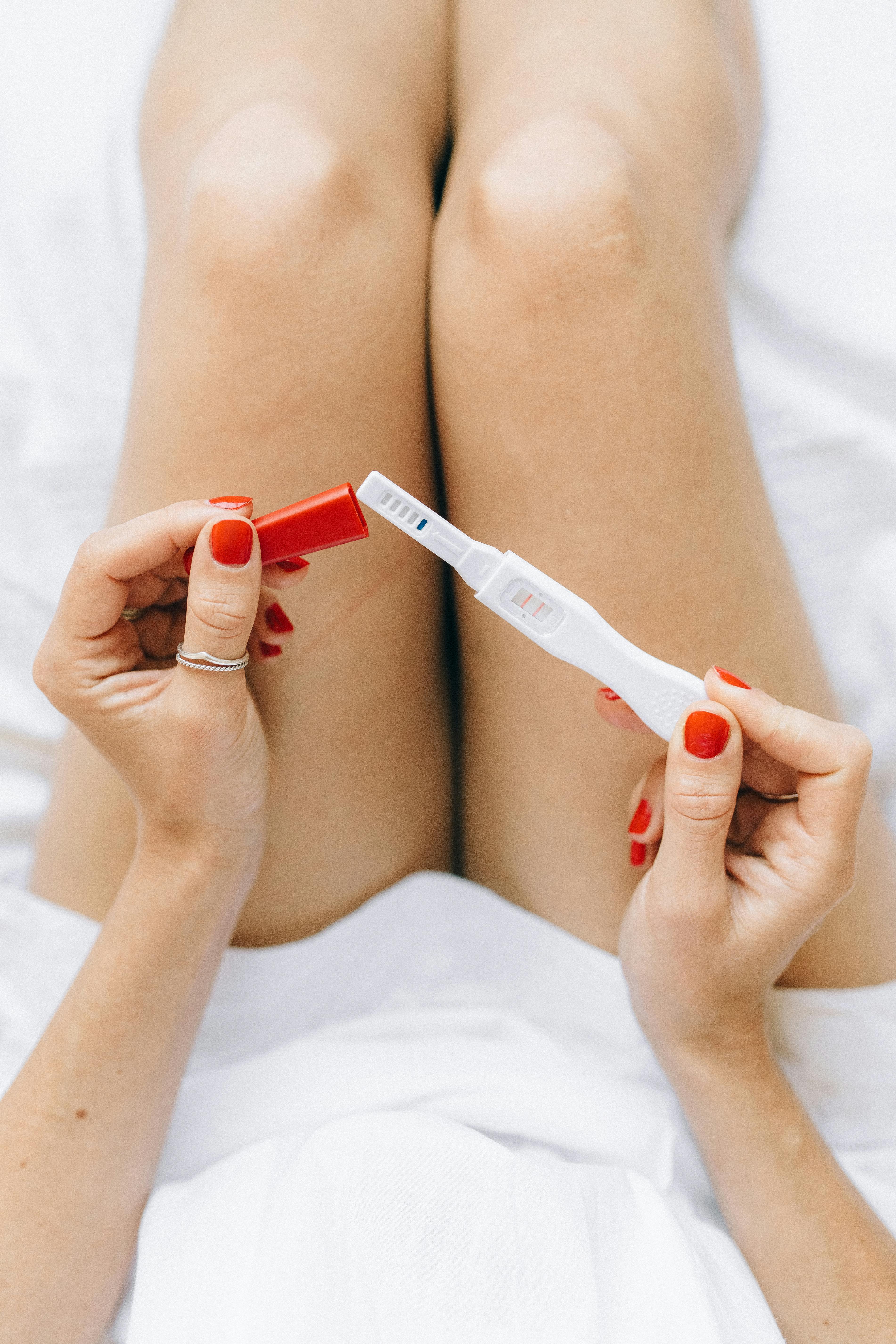 person in white dress holding a pregnancy test