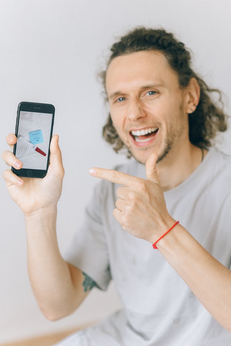 A Smiling Man Showing His Smartphone