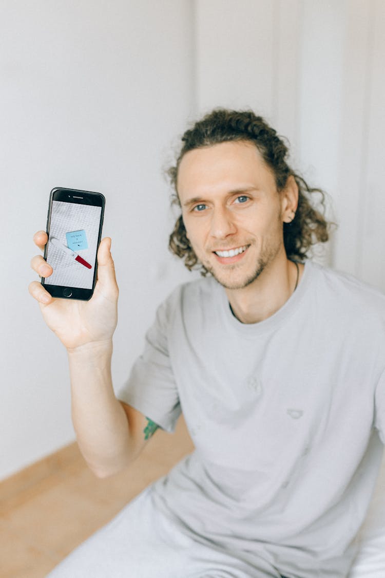 A Smiling Man Showing His Smartphone