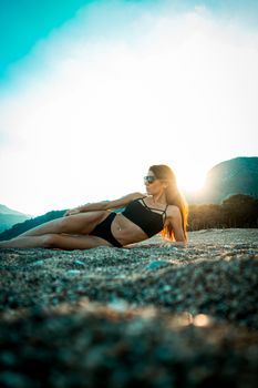 A woman in swimwear posing on the sand under sunlight, enjoying the summer vibes.