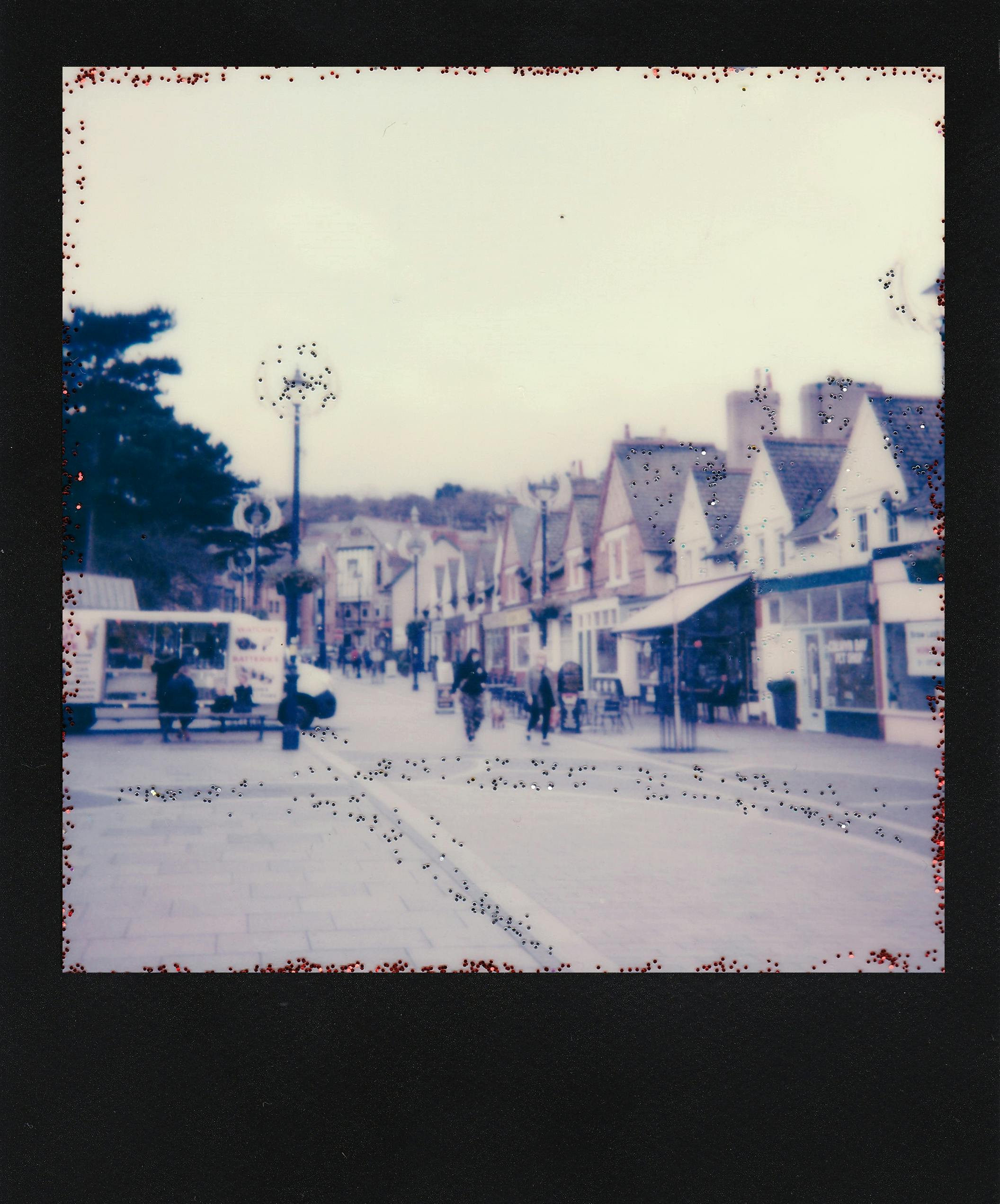 Retro-style Polaroid of a quaint town street capturing vintage architecture and daily life.