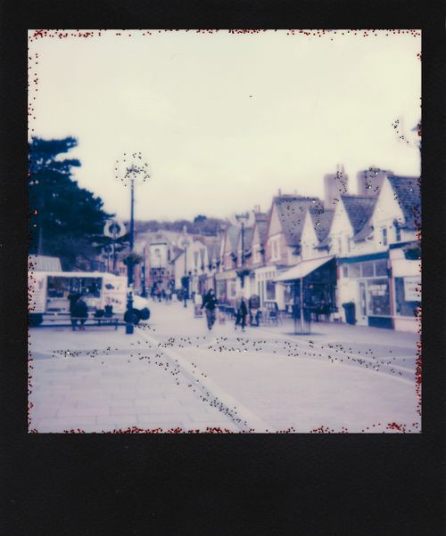 Free Retro-style Polaroid of a quaint town street capturing vintage architecture and daily life. Stock Photo