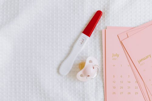Free White and Red Pregnancy Test Beside the Pink Pacifier  Stock Photo