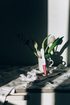 一个装有郁金香的陶瓷杯里放着验孕棒，柔和的光线和阴影照亮了它