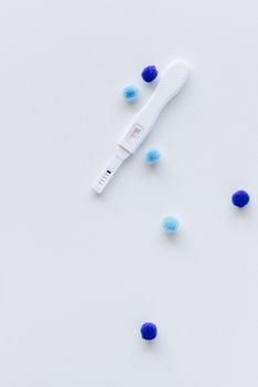 一张白色背景上呈现阳性结果的极简主义验孕棒图像，旁边有一根蓝色棒棒糖